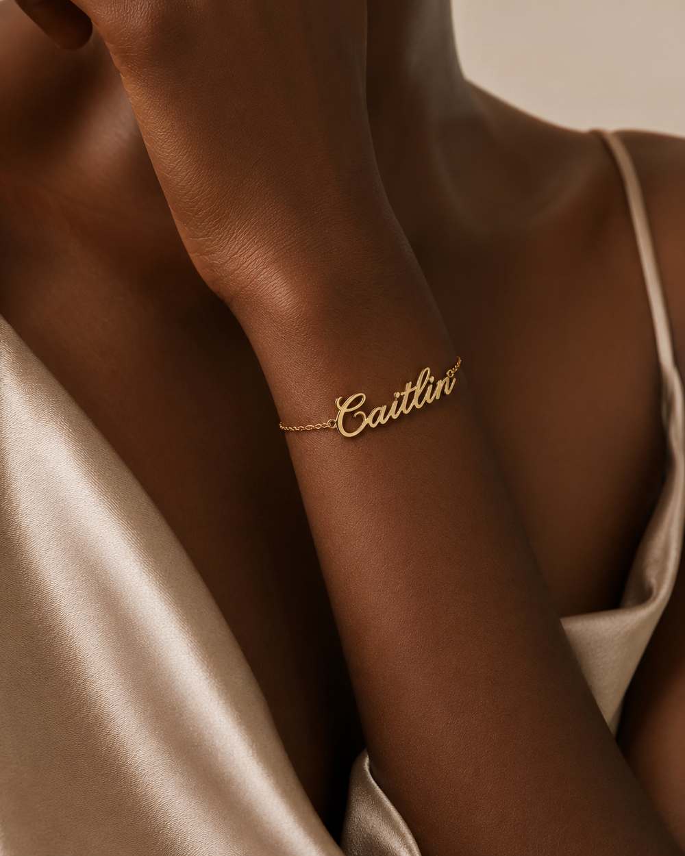 Close-up of custom gold script name bracelet on model