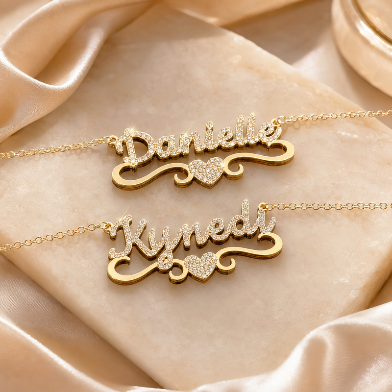 Danielle and Kynedi gold-tone crystal name necklaces on marble and satin