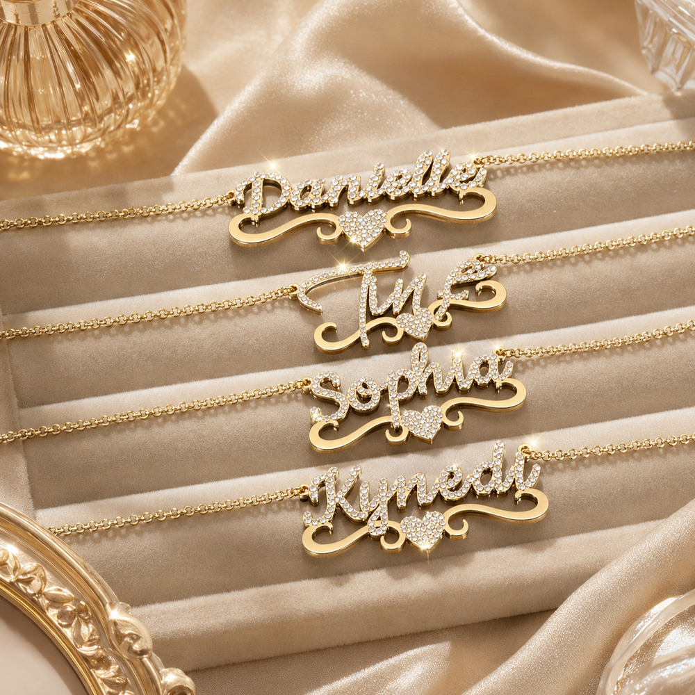 Four gold-tone crystal personalized name necklaces displayed on champagne velvet