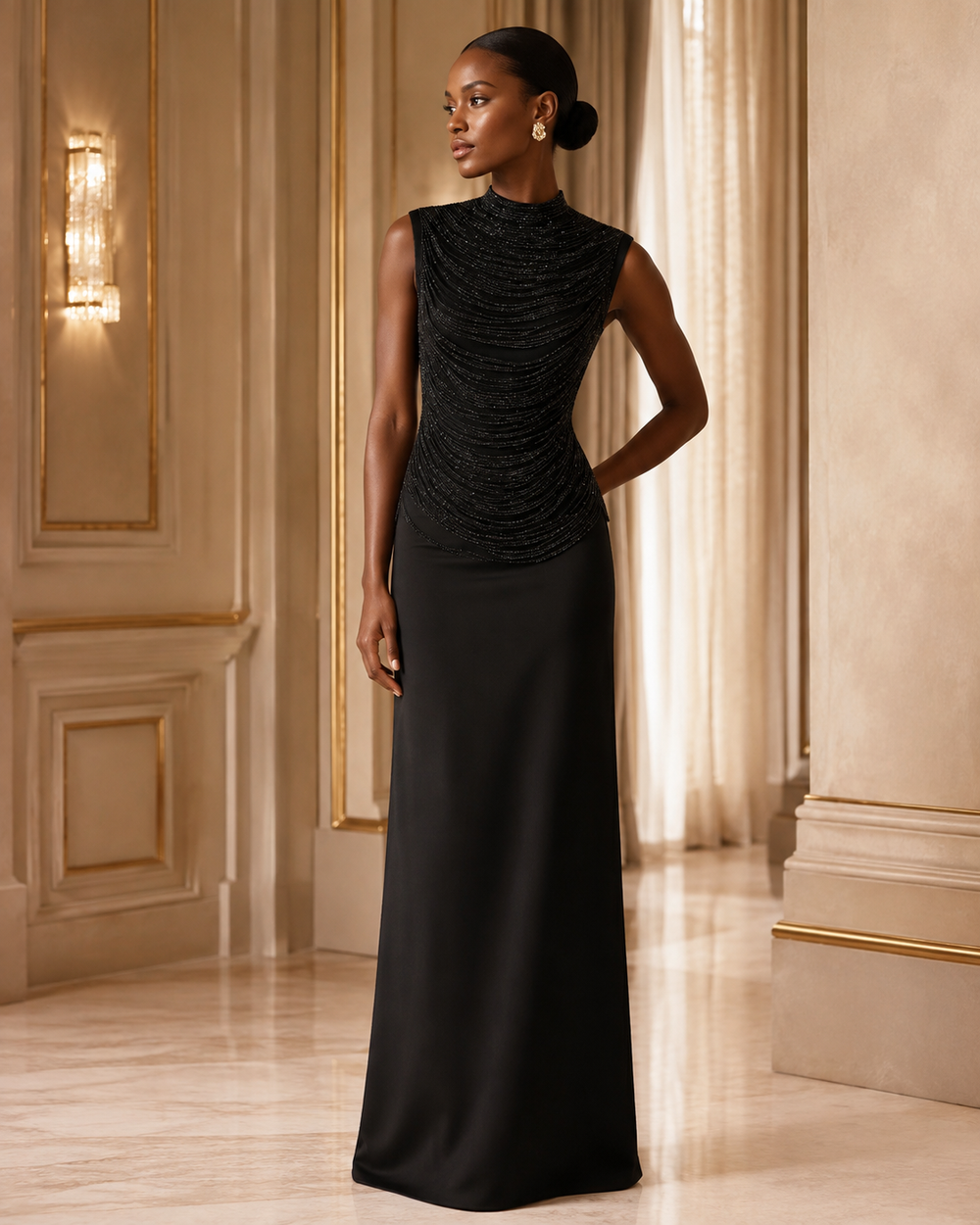A woman modeling a sleeveless black evening gown with a textured, ruched bodice and a floor-length skirt, standing in an elegant interior hallway with gold-trimmed walls and warm lighting.